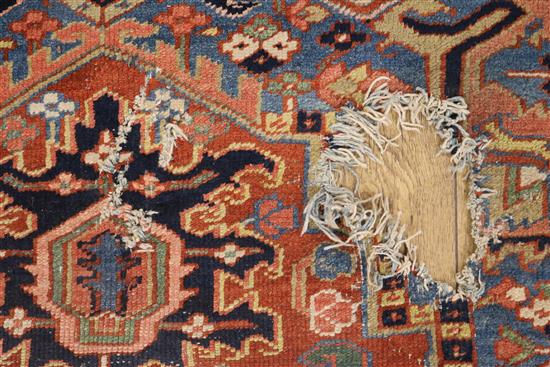 A Heriz brick red ground carpet (holed) 325 x 222cm